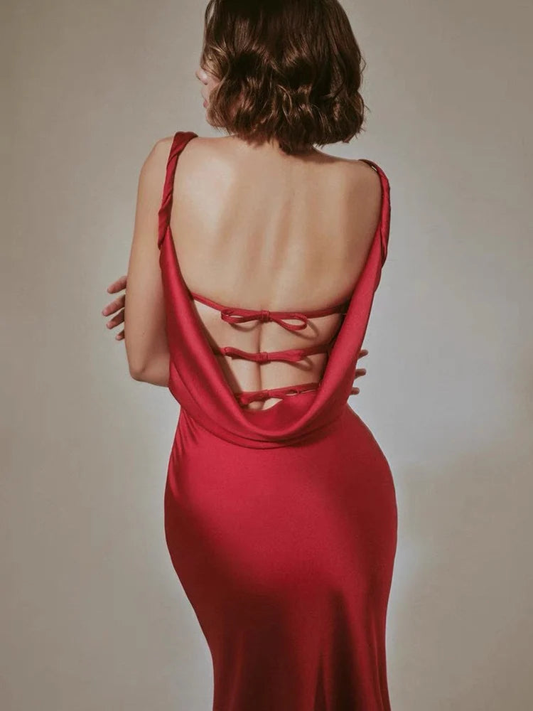 Woman wearing a red dress with an open back against a neutral background