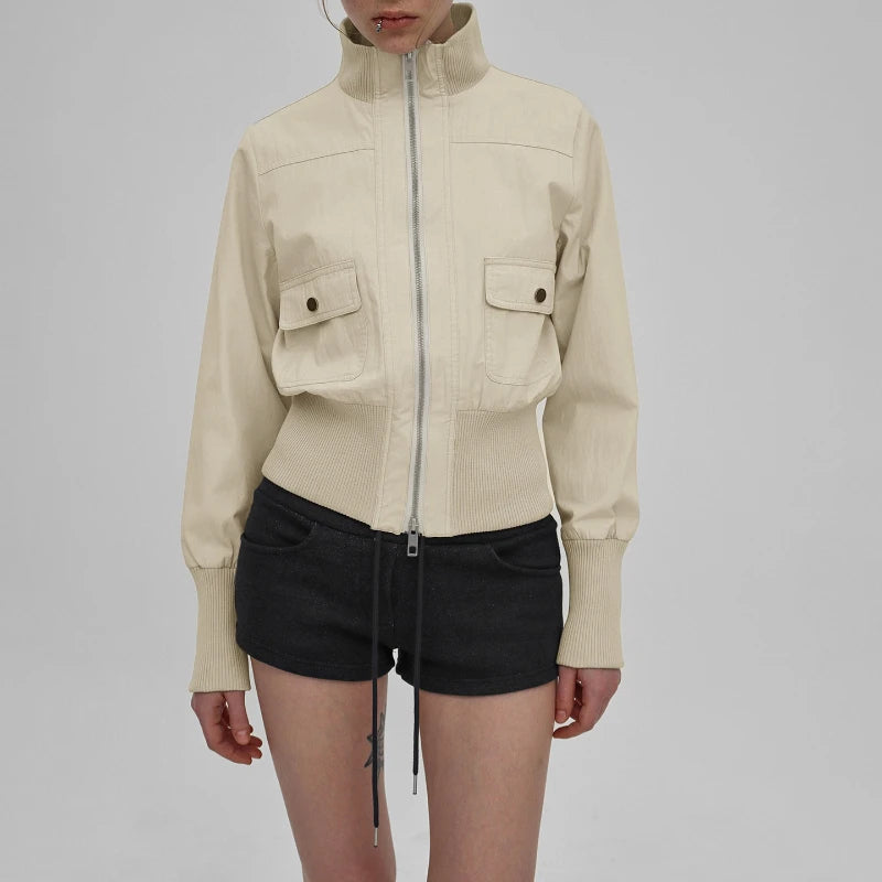 Person wearing a beige jacket and black shorts on a plain background