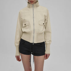 Person wearing a beige jacket and black shorts on a plain background