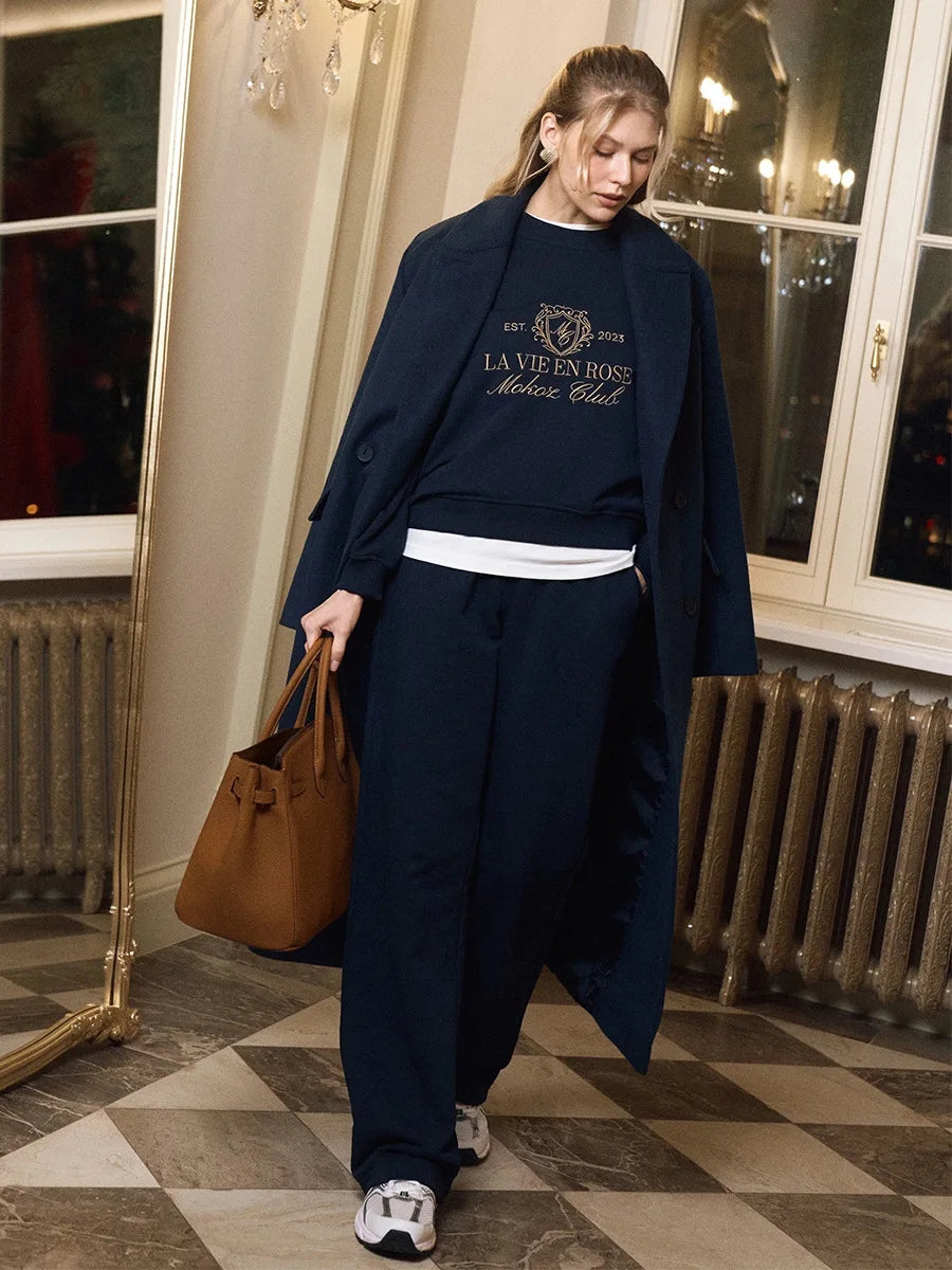 Person wearing a navy outfit with a brown bag in an indoor setting