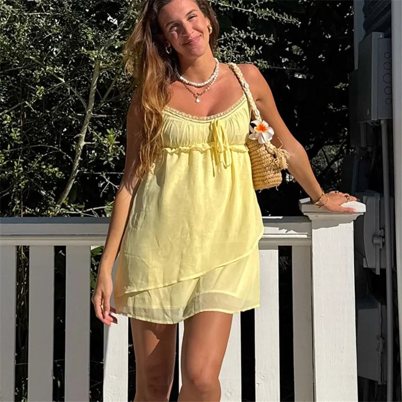 Woman in a yellow dress standing outdoors with greenery in the background