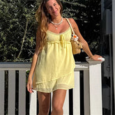 Woman in a yellow dress standing outdoors with greenery in the background