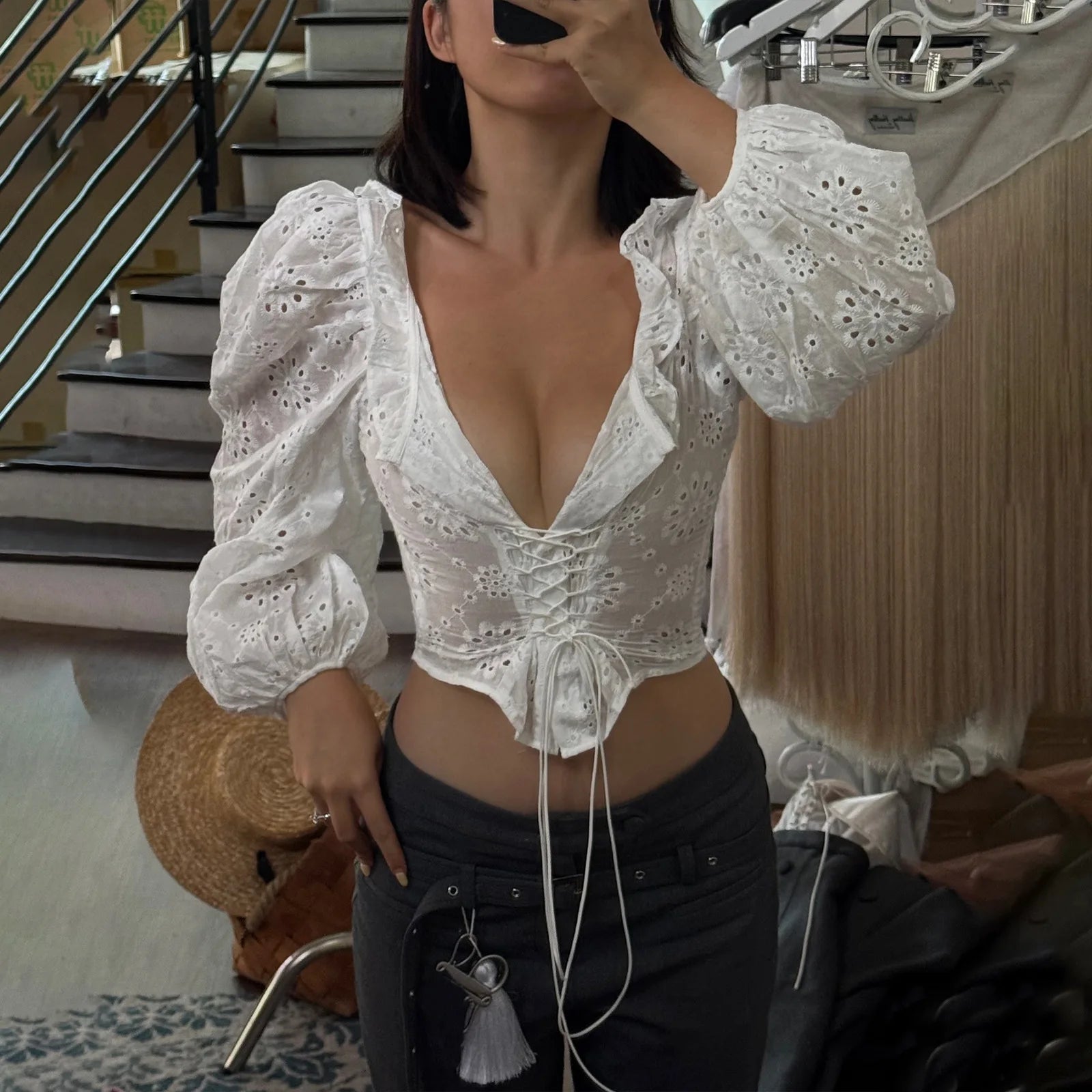 Person wearing a white lace top and black pants in an indoor setting.