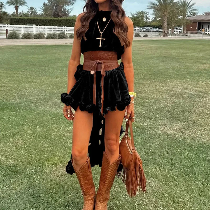 Woman in black top and brown skirt with knee-high boots standing on grass