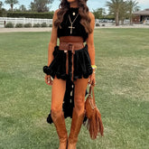 Woman in black top and brown skirt with knee-high boots standing on grass