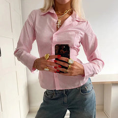 Person wearing a pink striped shirt and jeans, holding a phone with a white background
