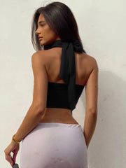 Woman wearing a black halter top and white pants- back view