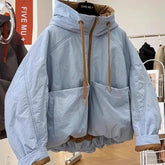 Light blue jacket with brown drawstrings on a hanger in a store setting.
