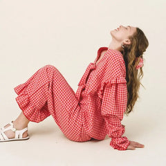 Woman wearing a red checkered outfit on a plain background
