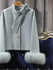 Light blue coat with fur cuffs on a hanger against a decorative background