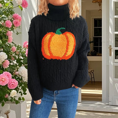 Person wearing a black sweater with a pumpkin design in front of a floral arrangement.