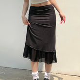 Person wearing a black and white polka dot skirt against a plain background