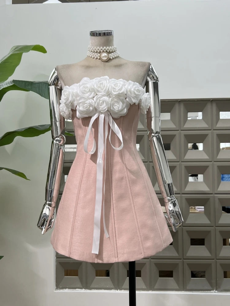 Pink dress with white floral top on a mannequin against a geometric wall.