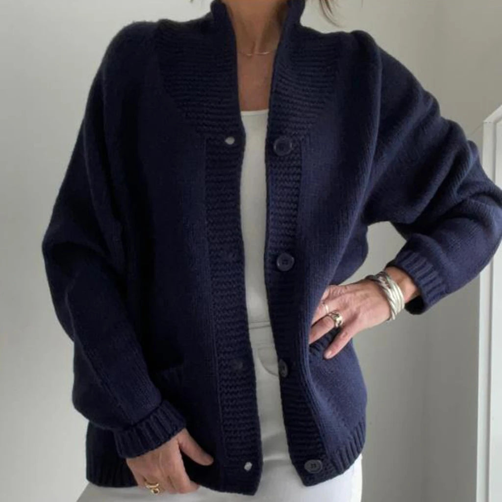 Person wearing a navy blue cardigan against a plain background