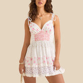 Woman wearing a white floral dress with pink accents on a beige background