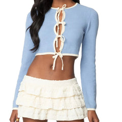 Light blue long-sleeve top with white lace-up detail and white ruffled skirt on a model.