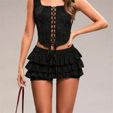 Black lace-up top and ruffled shorts on a neutral background