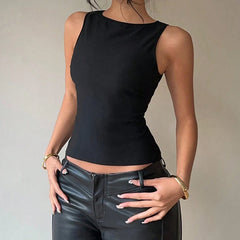 Person wearing a black sleeveless top and black leather pants against a neutral background