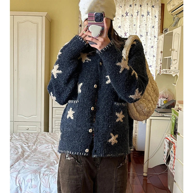 Person wearing a dark blue cardigan with star patterns in a room.