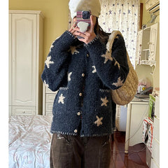 Person wearing a dark blue cardigan with star patterns in a room.