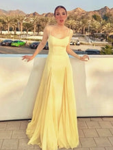 Woman in a yellow dress standing by a pool with mountains in the background