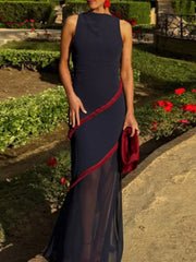 Woman in a navy dress with red trim standing in a garden.