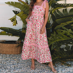 Woman wearing a pink floral dress standing in front of green plants- front view