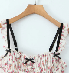 Floral top with black straps on a wooden hanger- close-up