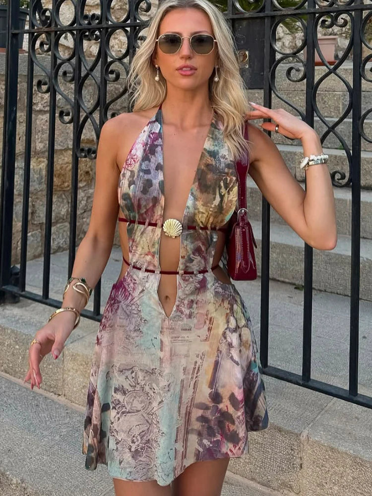 Woman in a patterned dress standing outdoors near a black metal gate.