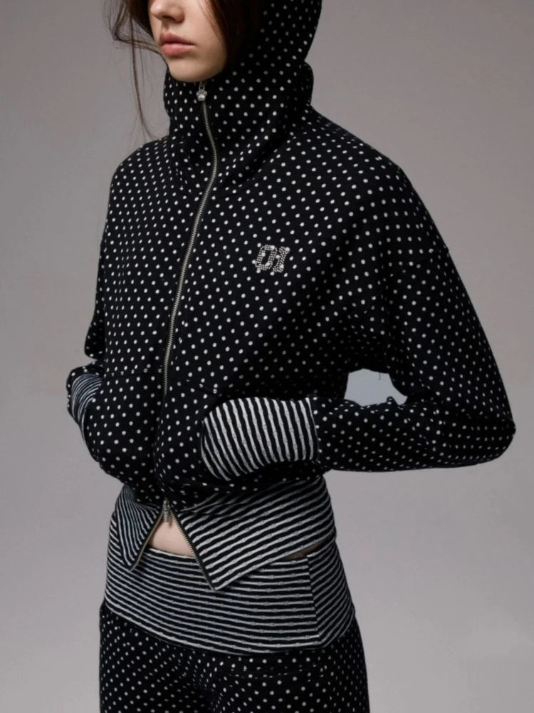 Person wearing a black and white polka dot jacket with a gray background