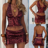 Woman wearing a red sequin dress with fringe details, accessorized with gold jewelry.