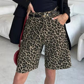 Person wearing leopard print shorts with a black top and coat in an indoor setting.