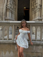 Woman in a white dress standing on a stone balcony with architectural background