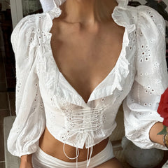 White lace top worn by a person, with a blurred background