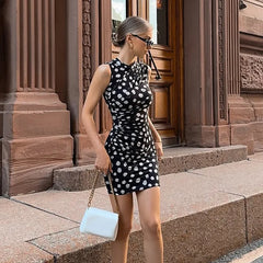 Woman in a black and white polka dot dress standing on steps in front of a building.