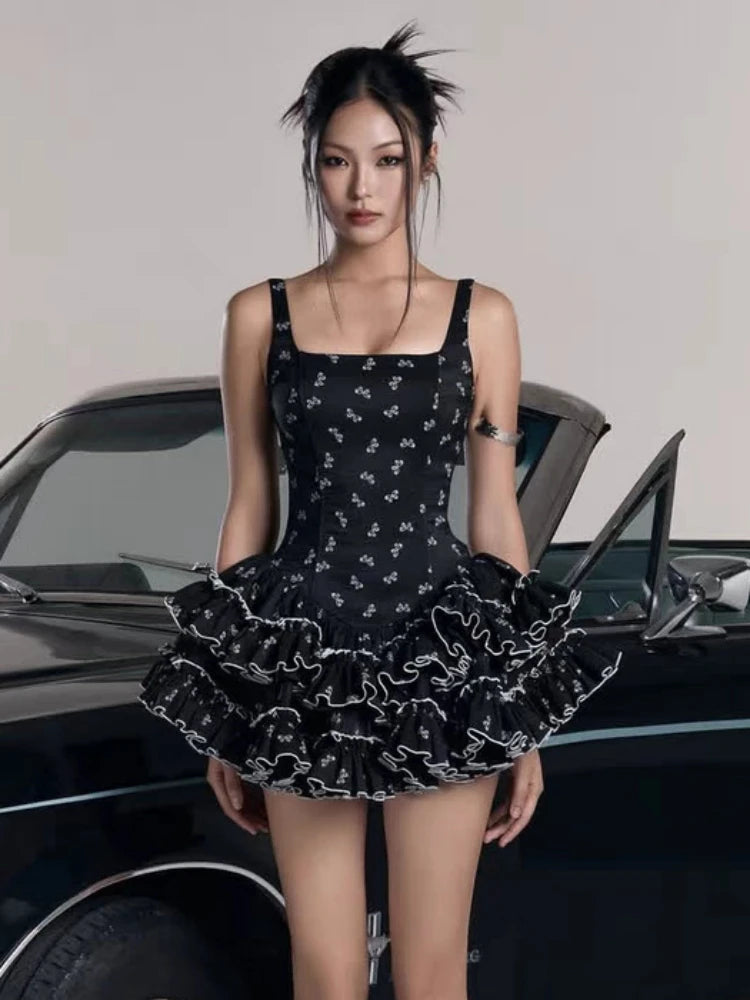 Woman wearing a black dress with white patterns in front of a car