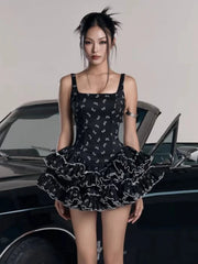 Woman wearing a black dress with white patterns in front of a car