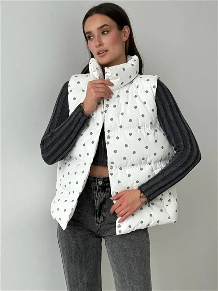 Woman wearing a white polka dot puffer vest over a black long-sleeve shirt on a gray background