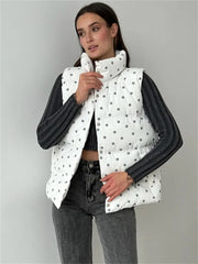 Woman wearing a white polka dot puffer vest over a black long-sleeve shirt on a gray background