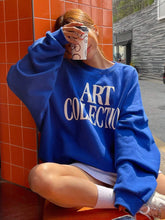 Person wearing a blue 'ART COLLECTION' sweatshirt sitting on an orange tiled floor.