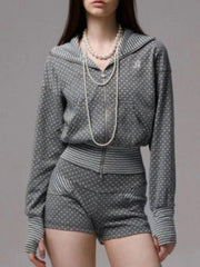 Person wearing a gray patterned outfit with a pearl necklace