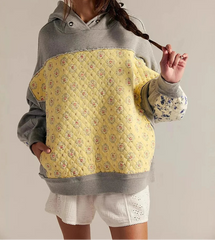 Person wearing a gray and yellow quilted hoodie with floral pattern