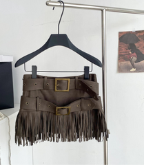 Brown fringe skirt with belt on a hanger against a white wall.