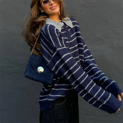 Woman wearing a blue and white striped poncho against a gray wall