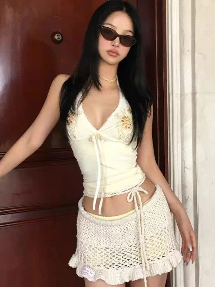 Woman wearing a white outfit with sunglasses in front of a wooden door.
