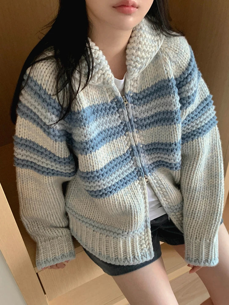 Person wearing a blue and white striped knitted cardigan indoors.