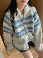 Person wearing a blue and white striped knitted cardigan indoors.