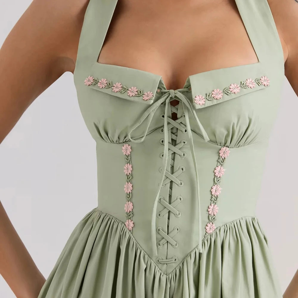 Women's green embroidered halter midi dress with A-line silhouette.