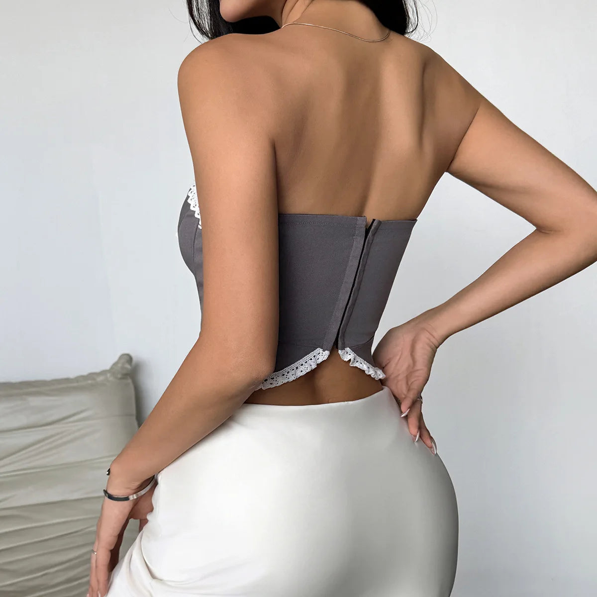 Person wearing a gray bodysuit with lace trim against a neutral background