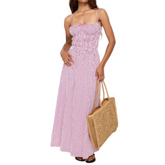 Woman wearing a pink and white striped dress holding a woven bag on a white background